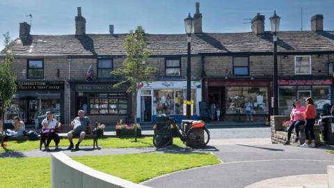 People sitting on benches in the sunshine in Ramsbottom town centre