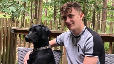 Cory Chilvers sat down and with his arm around a black dog