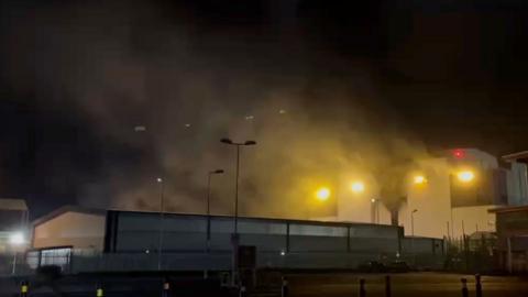 Screengrab showing plumes of black smoke coming out of a building at nighttime