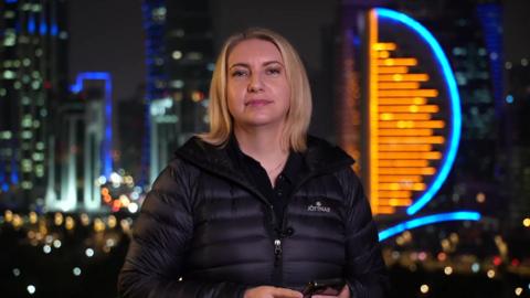 Anna Foster in Qatar with brightly lit buildings behind her