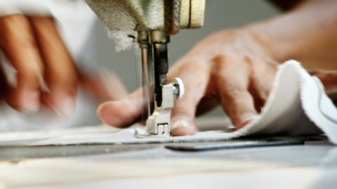 Stock photo: Close-up of worker sewing clothing in garment factory