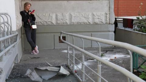 A woman checks her phone next to debris, following a reported drone attack in Krasnogorsk, Russia, August 22, 2023. REUTERS/Stringer