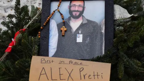 A picture of Alex Pretti is left at a makeshift memorial in the area where Pretti was shot dead a day earlier by federal immigration agents in Minneapolis, Minnesota, on January 25, 2026.