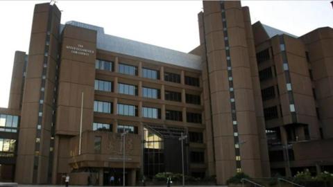 Liverpool Crown Court in Derby Square, with a sign saying 'The Queen Elizabeth II Law Courts' and another saying 'Liverpool Crown Court' above the entrance.