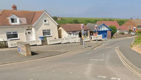 Houses and a cafe in Staithes, North Yorkshire, on a sunny day. A cafe has bunting across its entrance.