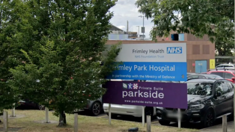A general view of Frimley Park Hospital, with cars parked behind it.
