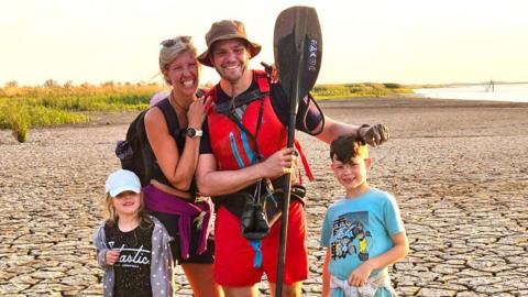 Mr Williams and his family by the side of a river, paddle in hand