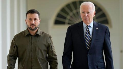 Zelensky and Biden walk side-by-side down a White House corridor.