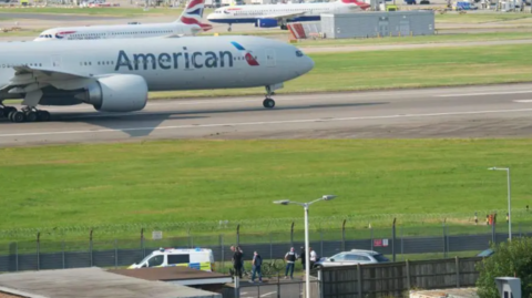 Heathrow Airport scene - a police vehicle and protestors can be seen airside 