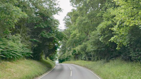 A general view picture of Common Hill in Englefield, a one-lane road with trees on either side. 