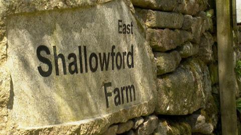 A close up of the sign for East Shallowford Farm on a traditional stone wall.