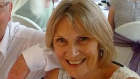 Lorna England smiling at the camera. She has short blonde hair and is wearing a white top. 