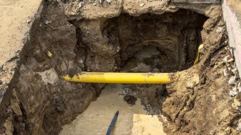 A yellow water pipe in a trench at a construction site.