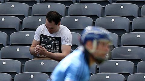 A spectator appears to be more interested with his mobile phone than a match between Dublin and Kilkenny