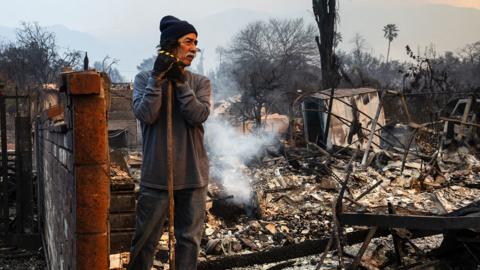 Man stands by burnt-out houses destroyed in Los Angeles fire 