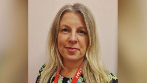 Julie Thomas has long blonde hair and is wearing makeup.