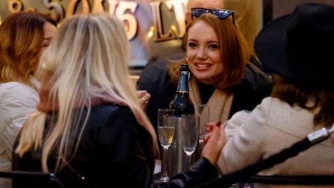 Customers enjoy drinks outside a pub in Covent Garden in central London on 18 December 2021