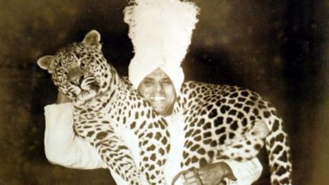Damoo Dhotre posing for a photograph carrying a leopard