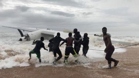 Rescuers pull the wreckage of the plane towards the shore near Abidjan, Ivory Coast, 14 October