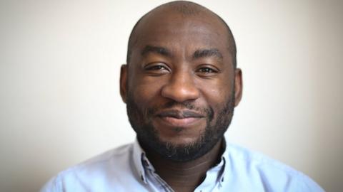 Headshot of Poku Osei smiling at the camera