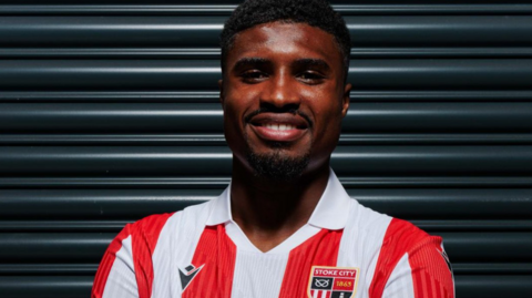 Ben Johnson poses in his red-and-white striped home Stoke City shirt