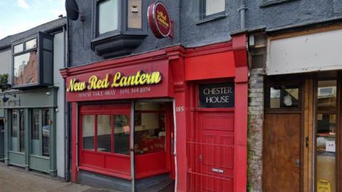 The entrance of New Red Lantern in Chester-le-Street. The takeaway front is red. New Red Lantern is written in yellow above the windows. 