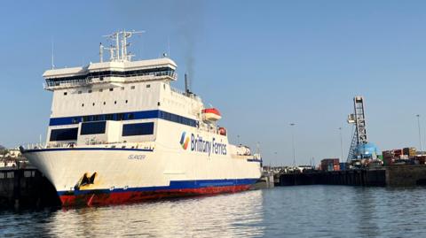 A front view of the large white Islander vessel with its blue and red trim. 