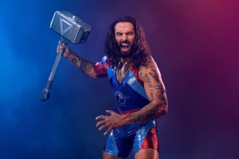 a promotional image of hammer holding up his giant hammer while looking menacingly at the camera