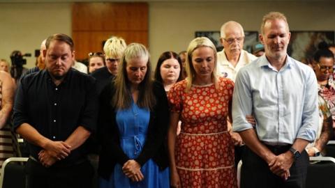 Gary and Sarah Andrews, and Sarah and Jack Hawkins and the Nottingham families take part in a minute silence, heads bowed.