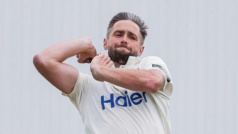 37-year-old Warwickshire bowler Chris Woakes shoulder and head shot mid-action wearing cricket whites and shlightly grey temples