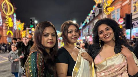 A photograph of three women celebrating Diwali on Belgrave Road in Leicester. 