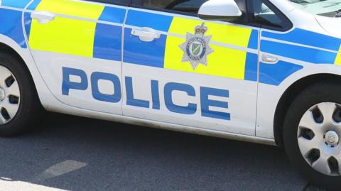 A Lincolnshire Police car parked by the side of a road. It has blue and yellow markings on and the Lincolnshire Police badge.