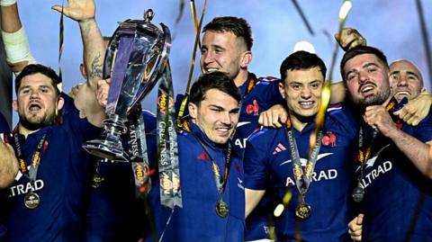 France's Antoine Dupont lifts the 2025 Six Nations trophy surrounded by team-mates