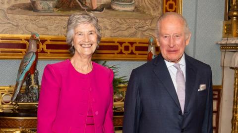 Irish president Catherine Connolly during an audience with King Charles III at Buckingham Palace in London, as part of her official visit to the UK. She has short white hair and wearing a pink dress and jacket. The king has short white hair, wearing navy blazer, white shirt and silver tie and pocket square.