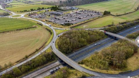 An artist impression from above of the proposed service station with lorries parked and the M180 junction in the foreground