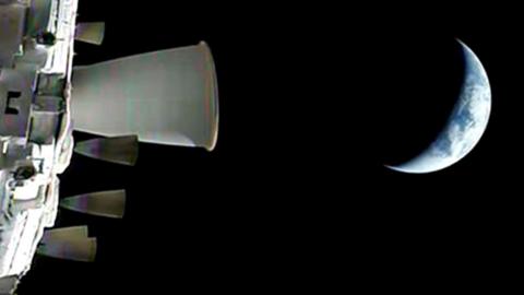 A view of the Earth from the spacecraft with part of the rocket in the foreground and the dark of space all around