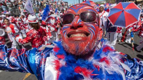 A man with blue, red and white face paint smiles broadly at Cape Town's Tweede Nuwe Jaar festival - Saturday 4 January 2025