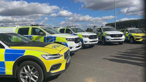 Marked yellow and white police cars from the Lincolnshire Police Rural Crime Team arranged in a semi circle
