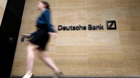 Pedestrian walk past the offices of of German bank Deutsche Bank in central London on July 8, 2019.