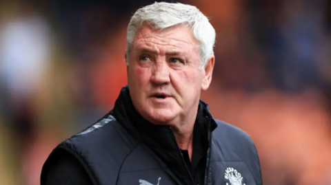 Steve Bruce, who has grey hair, on the touchline at a Blackpool match wearing a black gilet with the club crest over a dark long-sleeved top.