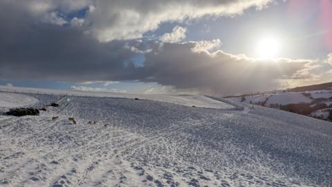 snow on a hill in a field.