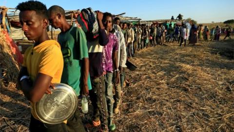 Ethiopian refugees who fled Tigray region, queue to receive food aid within the Um-Rakoba camp in Al-Qadarif state, on the border, in Sudan December 11, 2020.