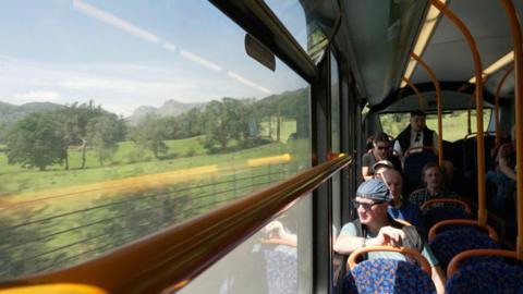 A view out of the window of a moving bus, with Cumbrian countryside visible.