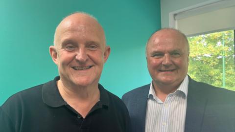 Two bald men smiling