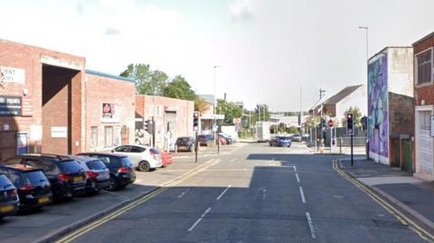 Cross roads with cars lined up on the left and car turning in distance