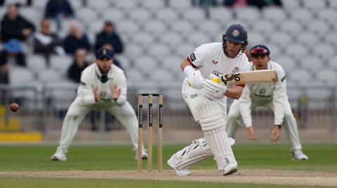 Marcus Harris clips the ball square on the on side and begins to run, wearing blue helmet with red rose emblem. Two opposition fielders are seen fielding in the slips behind him