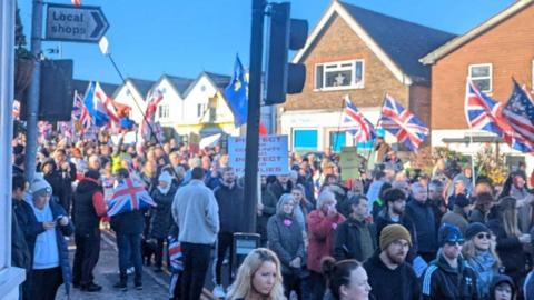 A crowd of people holding flags and signs. 