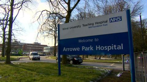 A blue and white NHS sign at the entrance to hospital grounds; the sign reads 'Welcome to Arrowe Park Hospital' 