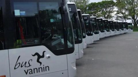 A row of silver Mercedes single decker buses, the closest has a Bus Vannin logo, which features a black three legs of Man, on the side.