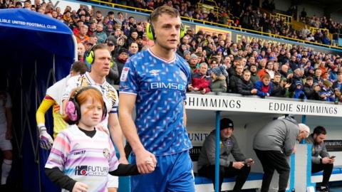 Serena McCarron being led onto the pitch by Carlisle United player Sam Lavelle